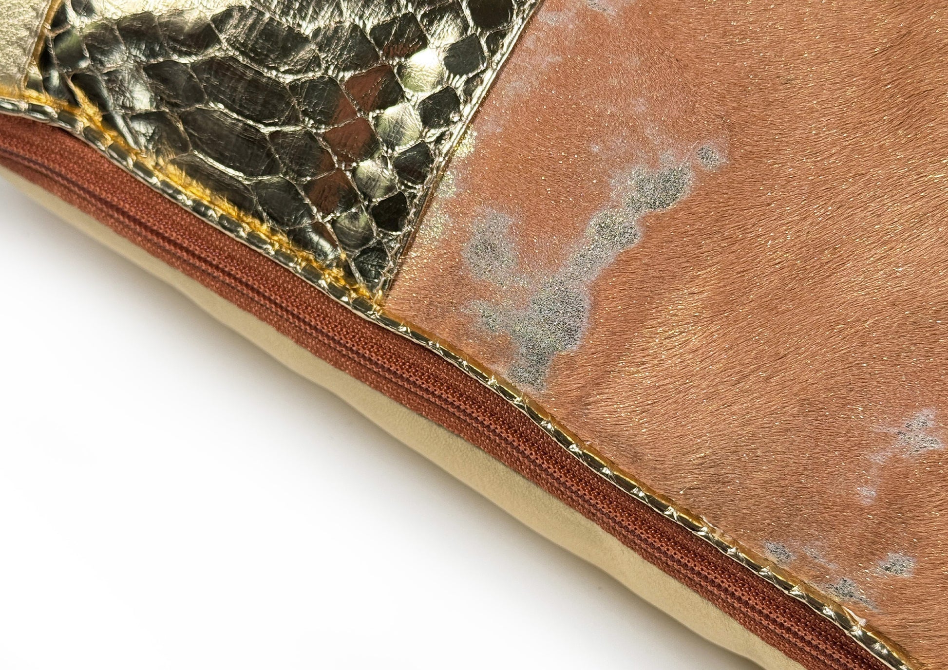Close-up of the amber zipper detail on the Amber Crown Large luxury cushion, crafted from amber-gold calf leather, gold python, and sheepskin.
