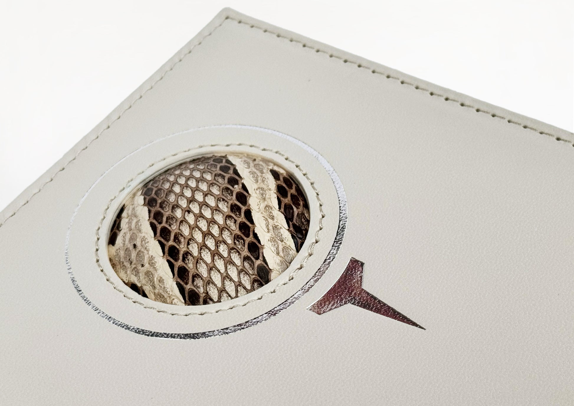 Close-up of the embossed golf tee motif and circular python insert on the Carte du Jeu scorecard holder, symbolizing sport and craftsmanship.